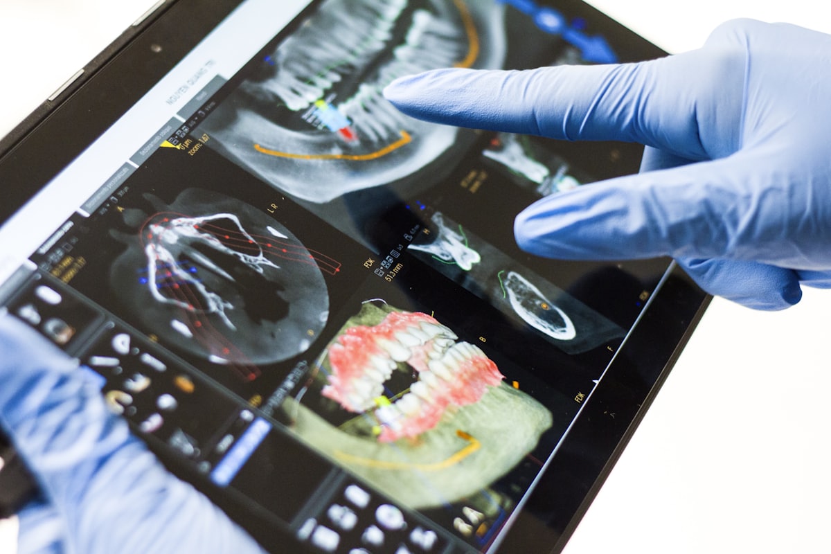 Gloved hands reviewing a 3D dental scan on a tablet